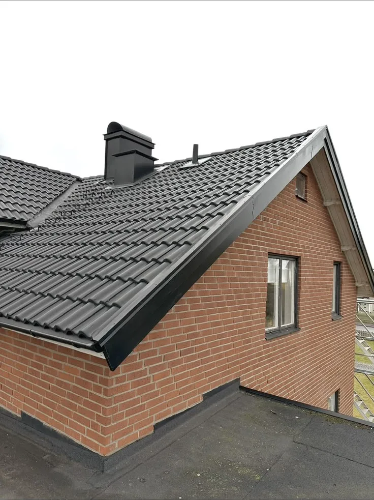 Svart tak och plåtbeslag på tegelhus