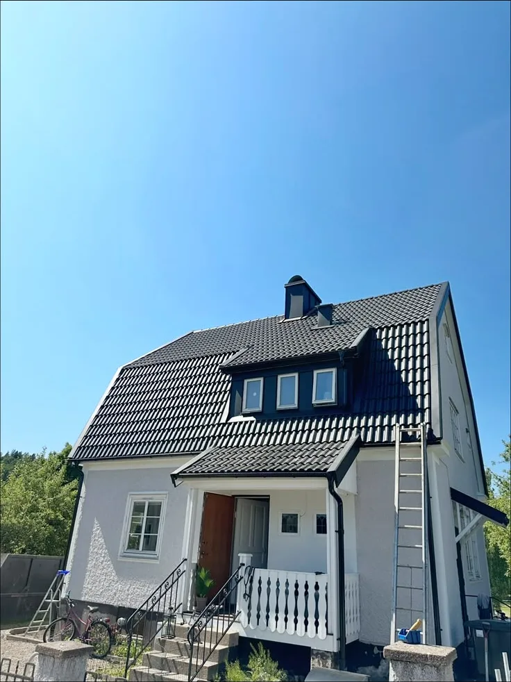 Svart tak med takkupa på vit villa